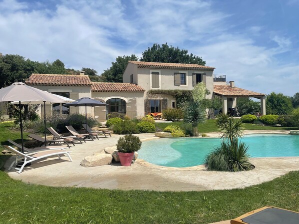 Une grande maison avec une piscine, un espace extérieur aménagé et un jardin bien entretenu.