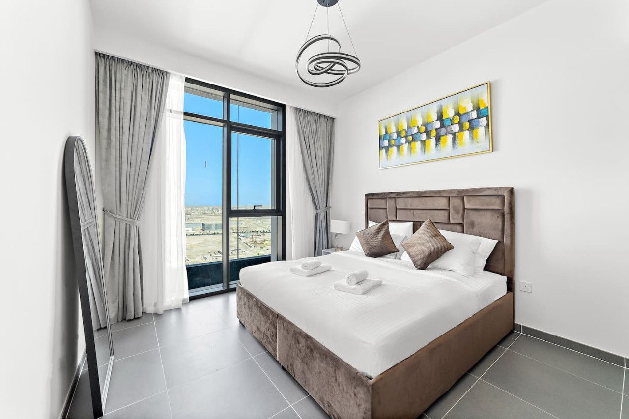 Une chambre d’hôtel moderne avec un grand lit, une vue sur la ville et une œuvre d’art contemporaine accrochée au mur.