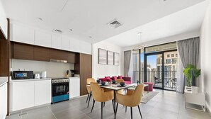 A modern kitchen with a dining area, a balcony with a city view, and a living space with a sofa and chairs. - HomesVIP | High-Class | Brand New (Dubai)