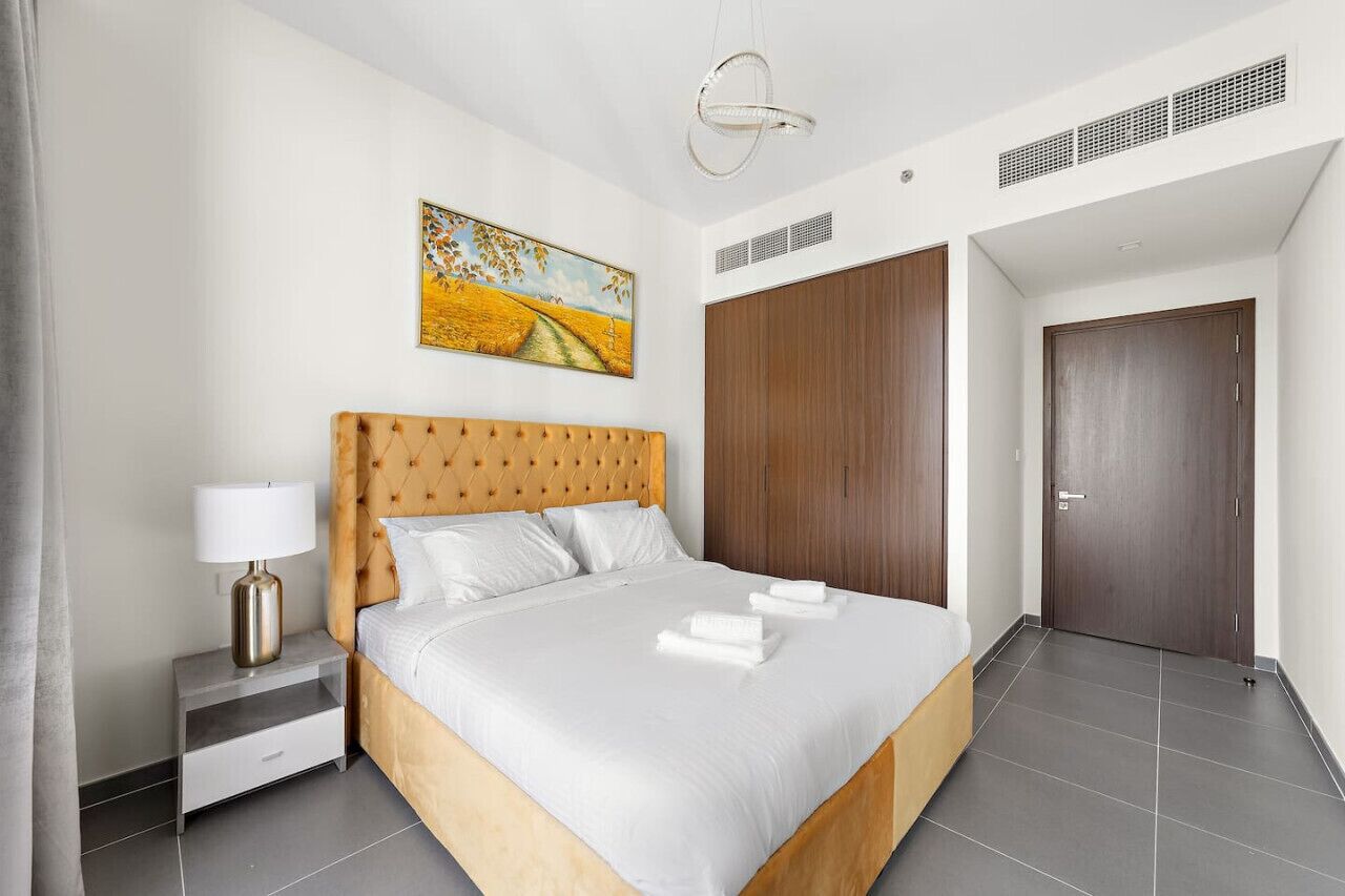 Ein modernes Hotelzimmer mit einem großen Bett, einem Nachttisch, einem Gemälde, einem Kleiderschrank und einer Tür.
