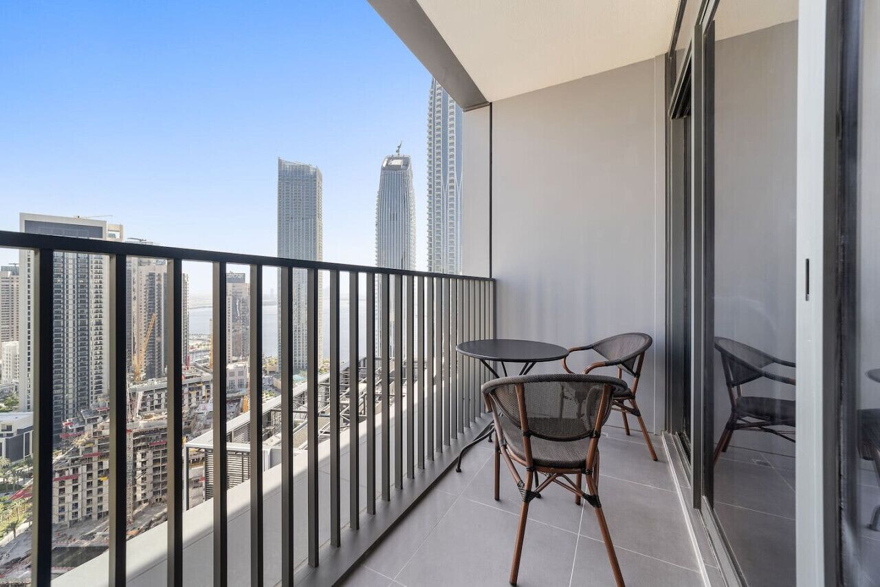 A balcony with a city view, two chairs, and a small table.