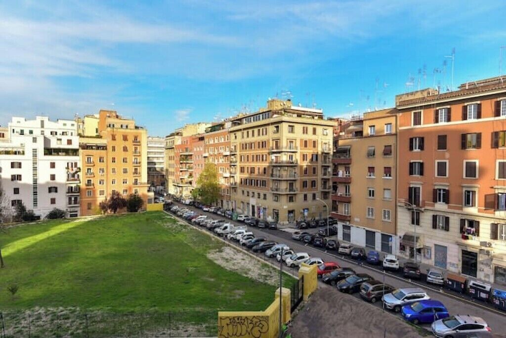 Une rangée d’immeubles à plusieurs étages, avec un parking devant.