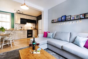 A modern living room with a grey sofa, a wooden coffee table, and a dining area with a white table and chairs. - Lovely Portobello Apartment near Westbourne Park (London)