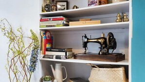 Una estantería con libros, una máquina de coser y objetos decorativos.