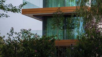 Ein modernes, mehrgeschossiges Gebäude mit Glasbalkonen und einer Fassade aus Glas und Holz.