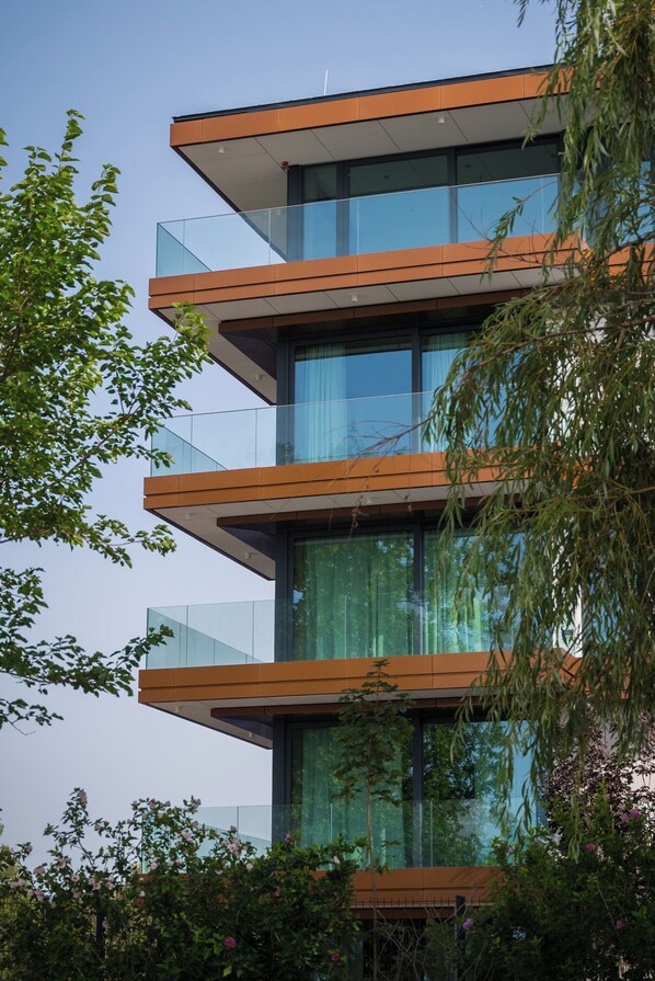 A modern multi-story building with glass balconies and a mix of glass and wooden facade elements. - BJ81 Suite Hotel (Siófok)