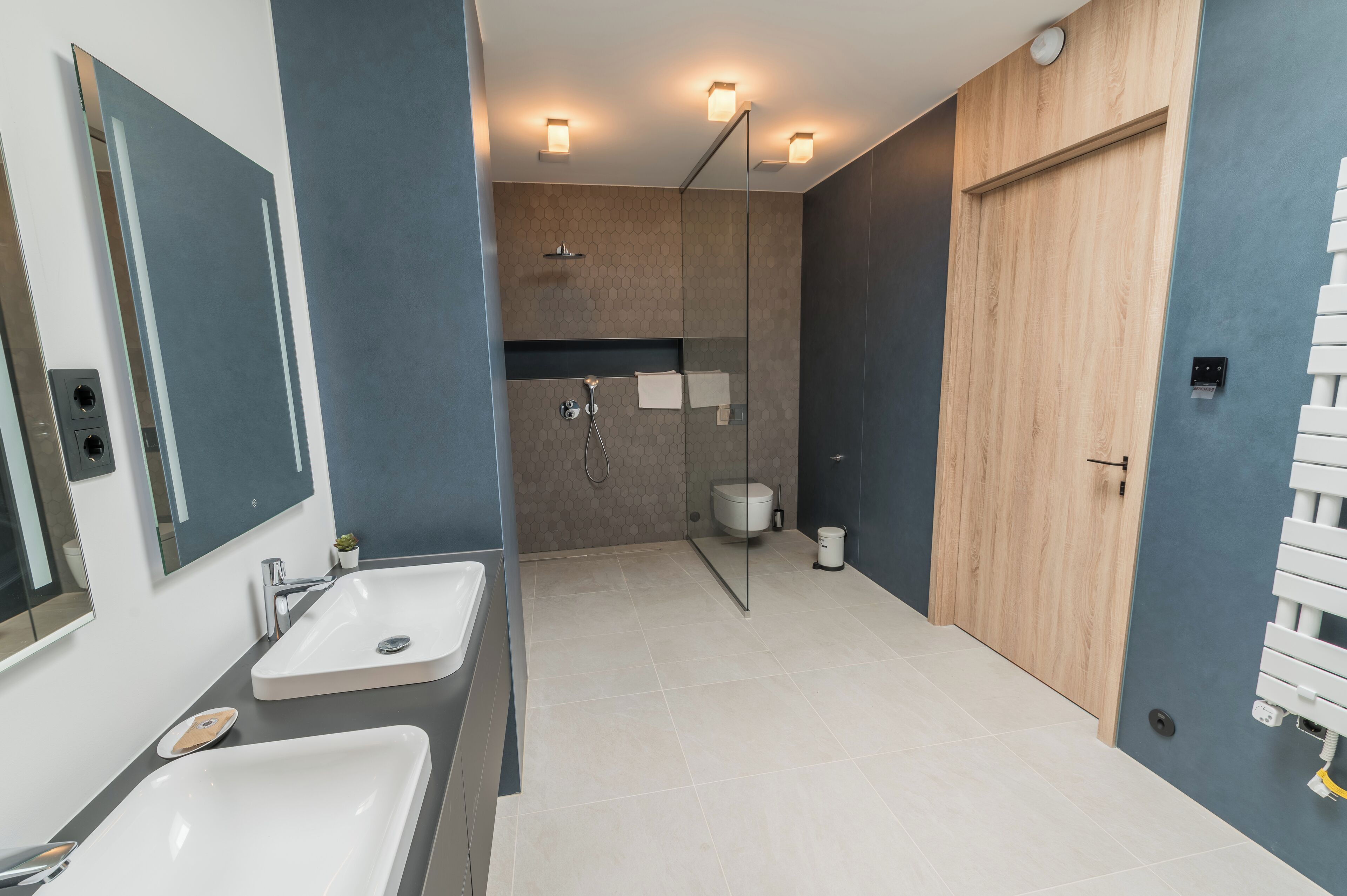 A modern bathroom with two sinks, a shower, and a toilet.
