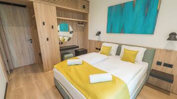 Ein modernes Hotelzimmer mit einem großen Bett, einem Schreibtisch, einem Spiegel und einem Gemälde an der Wand.