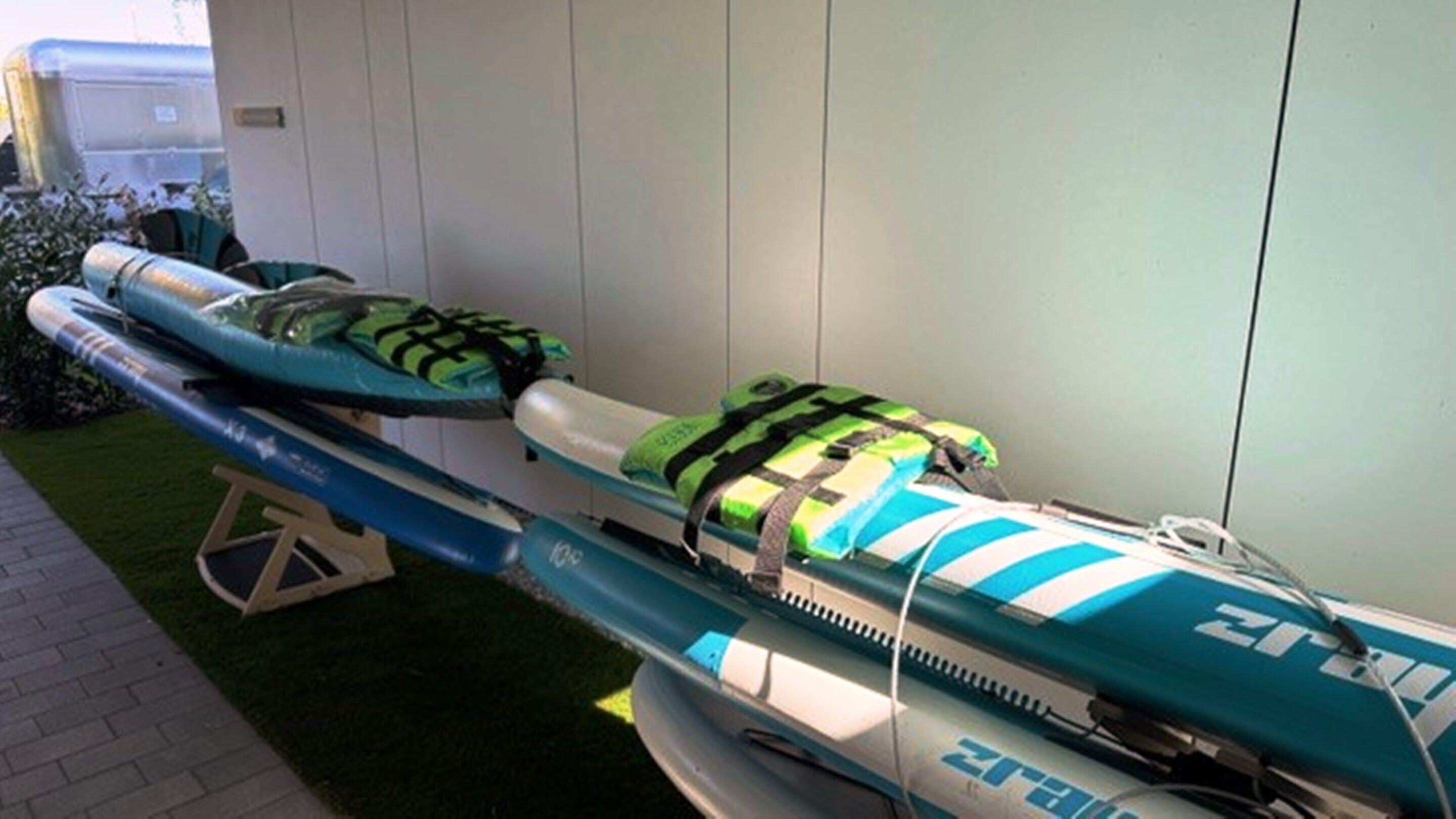 Dos kayak amb chalets salvavides i una taula de surf recolzada contra una paret.