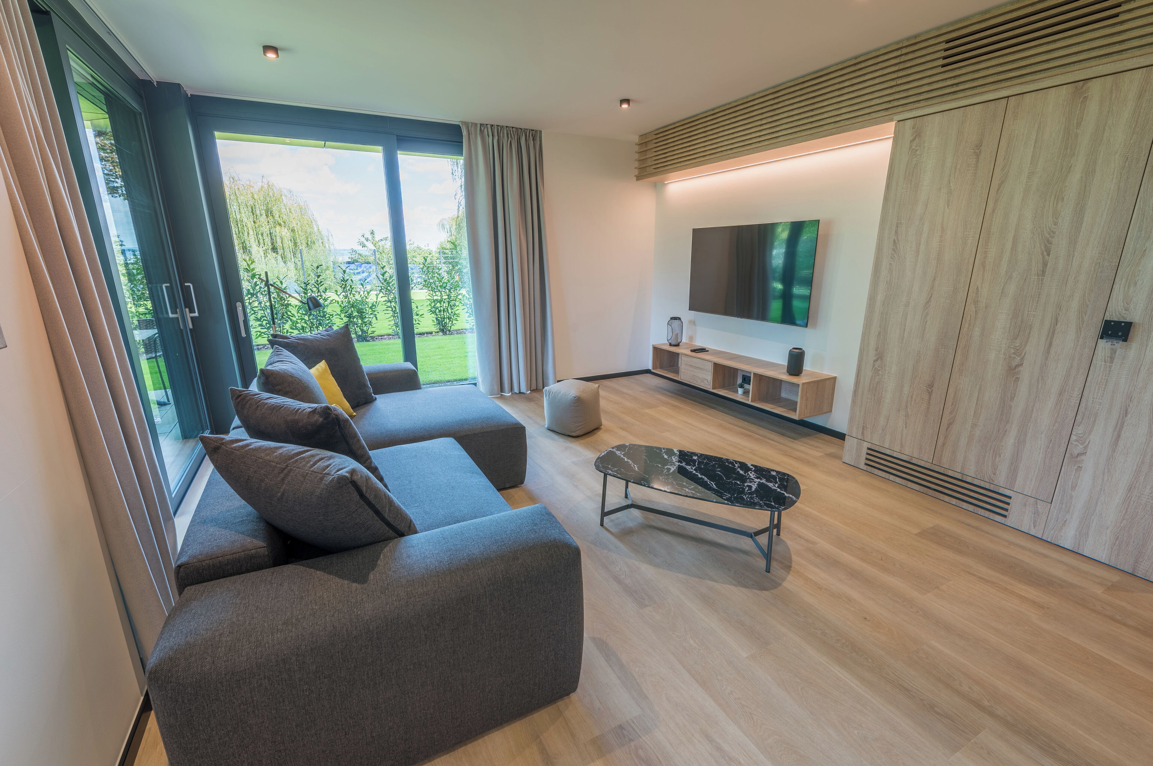 A modern living room with a sofa set, a coffee table, and a TV mounted on the wall.