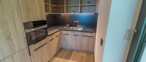 Una cocina moderna con armarios de madera, horno empotrado y un fregadero.