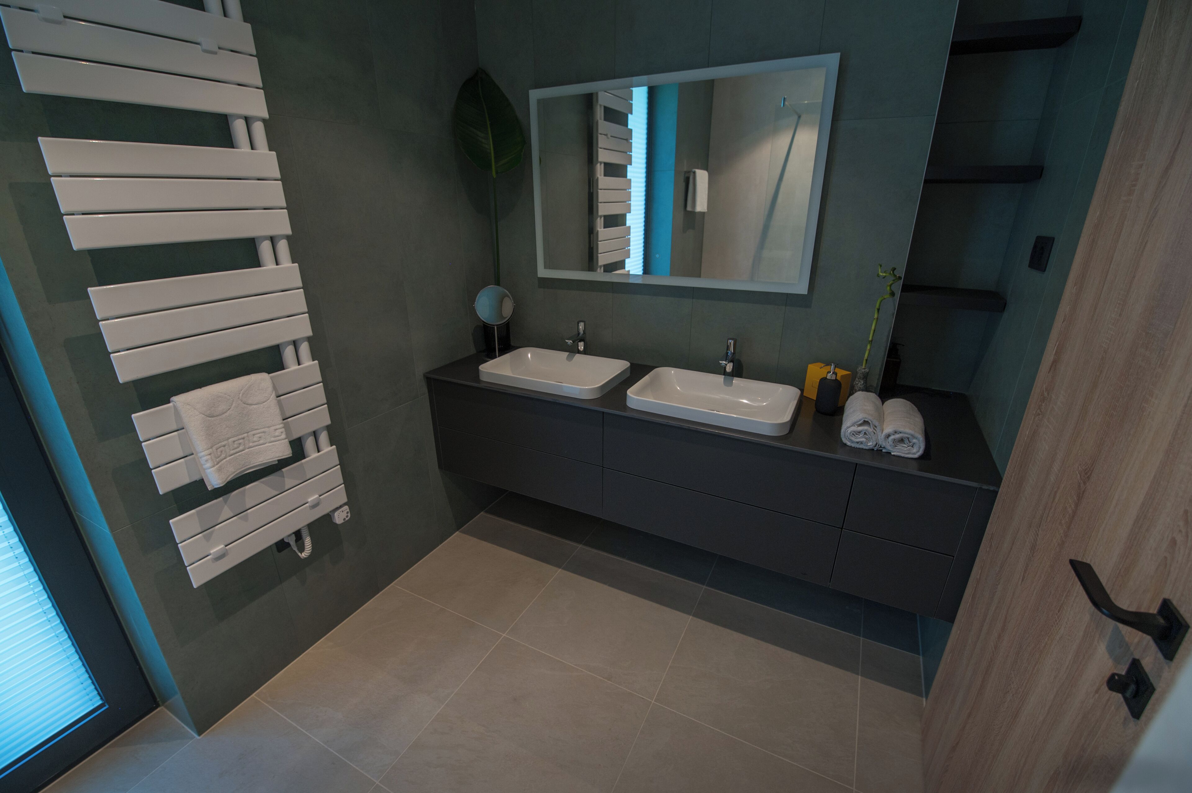 A modern bathroom with two sinks, a large mirror, and a towel rack.