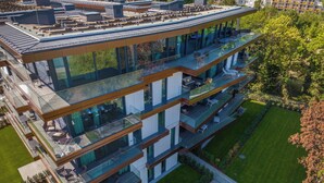 A modern multi-story building with glass balconies, a swimming pool, and a well-maintained lawn. - BJ81 Suite Hotel (Siófok)