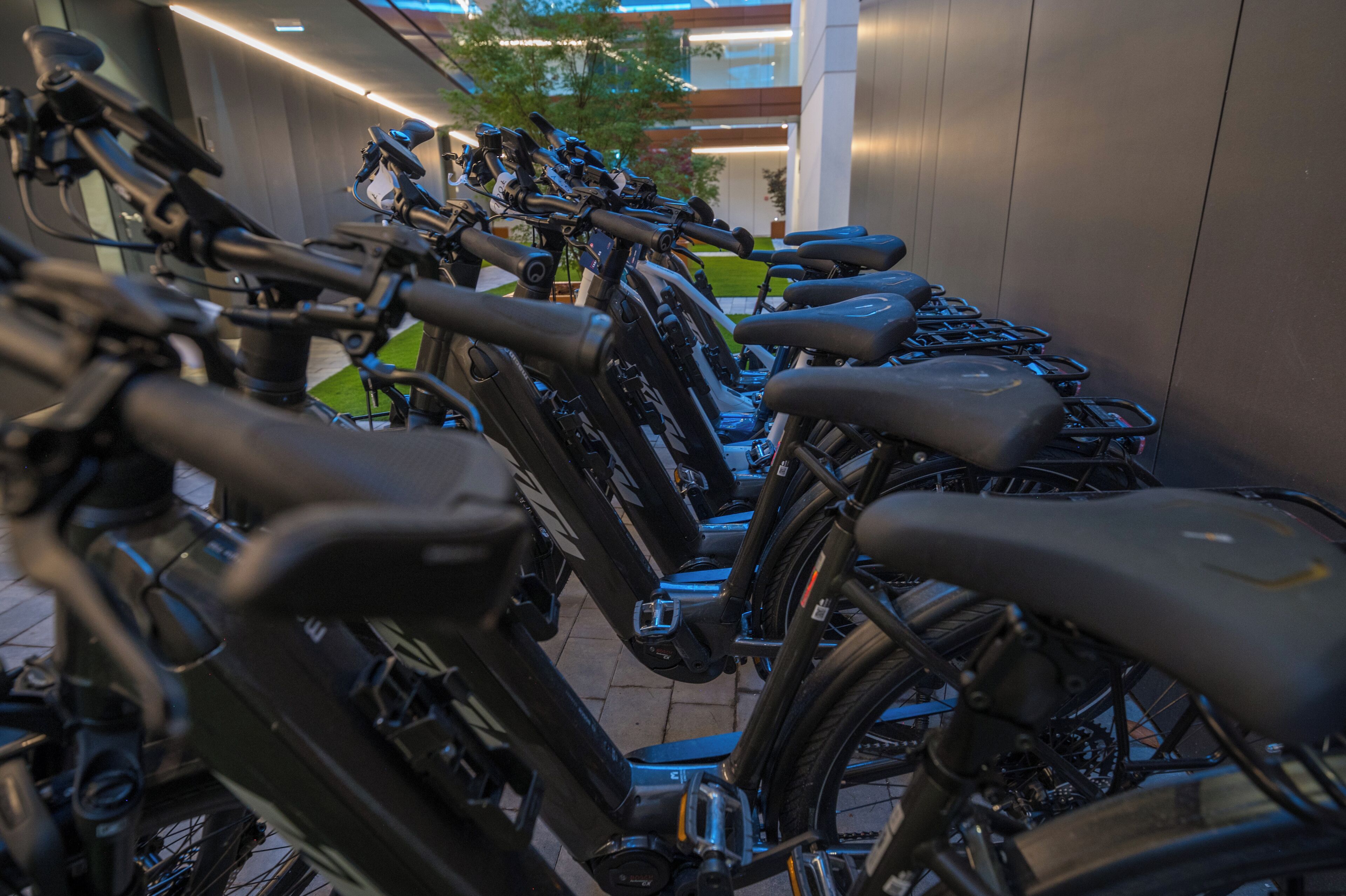 A row of stationary bicycles parked in an indoor area with a modern design, likely a bike-sharing station.