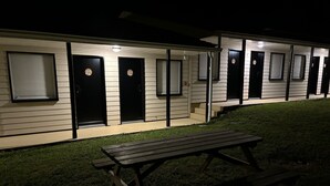 A row of motel rooms with numbered doors, a picnic table, and a grassy area. - Halte Hotel (La Vergne)