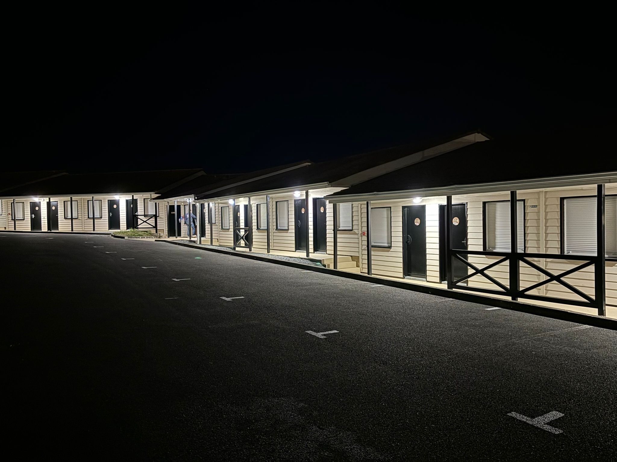 Eine Reihe von motelähnlichen Gebäuden mit separaten Zimmern, jedes mit einer Tür und einem Fenster.
