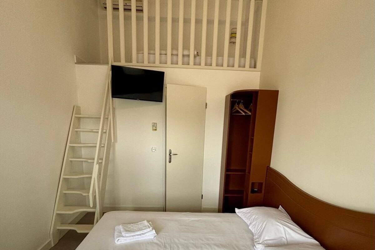 Ein Hotelzimmer mit Bett, Wand-Fernseher, Kleiderschrank und einer Treppe zu einer oberen Ebene.