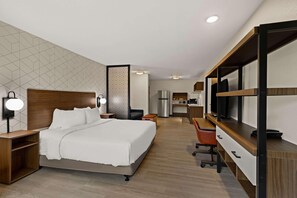 Une chambre d’hôtel équipée d’un lit, d’un bureau, d’une chaise et d’une kitchenette.