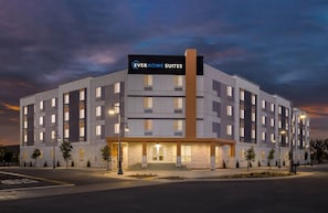 A modern hotel with a sign reading 'EVERHOME SUITES' and a symmetrical facade with evenly spaced windows.