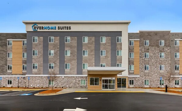 Un hotel de varios pisos con fachada de piedra, techo plano y entrada central.