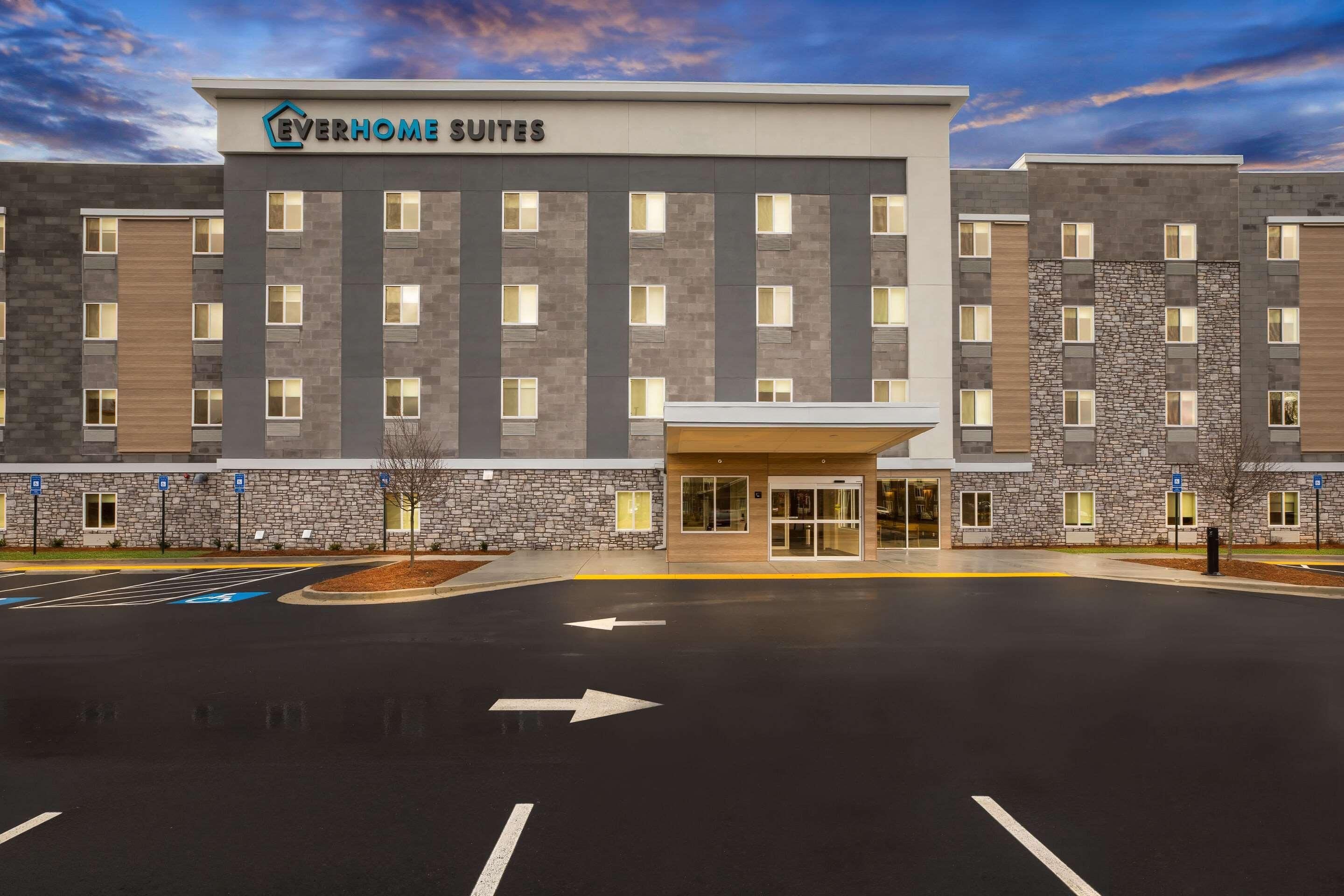 A hotel with a modern facade, multiple floors, and a parking lot with directional arrows.