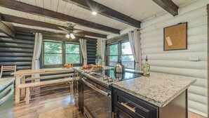 A log cabin interior with a kitchen island, wooden benches, and a ceiling fan.