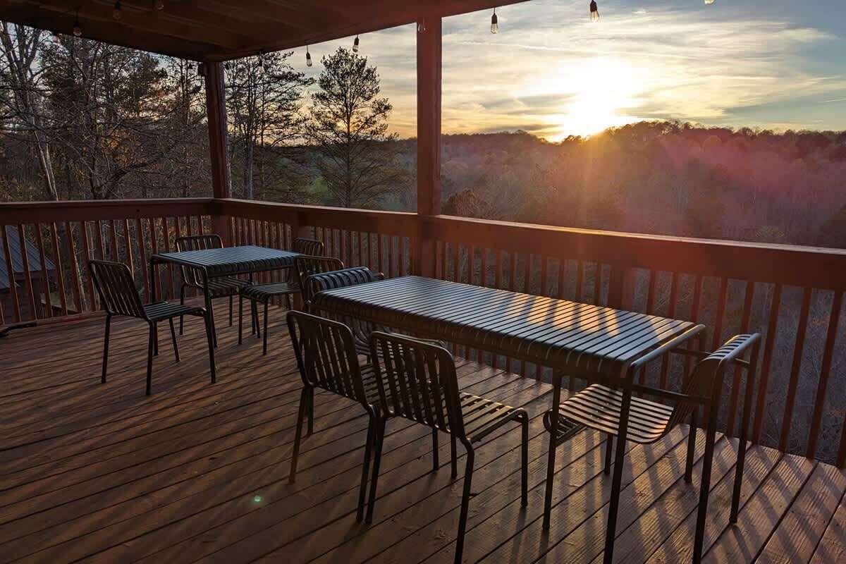Una terraza de madera con una mesa y sillas, con vistas a una zona boscosa.