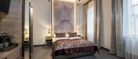 Une chambre d’hôtel moderne avec un grand lit, des tables de chevet, un miroir et un panneau fixé au mur.
