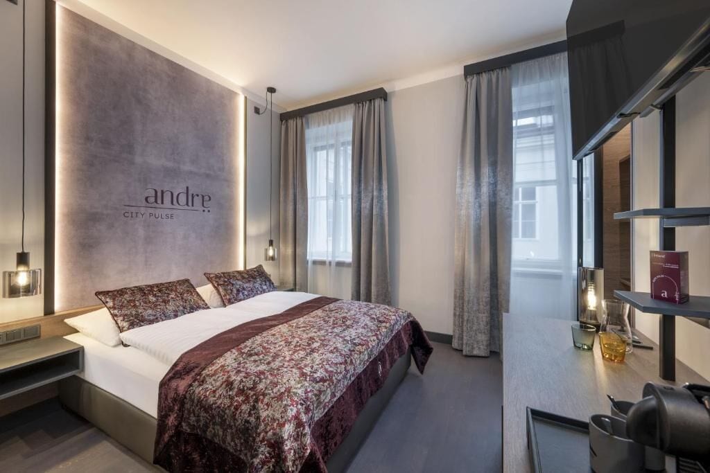 Una habitación de hotel moderna con una cama grande, una mesita de noche, un escritorio y vistas a la ciudad.