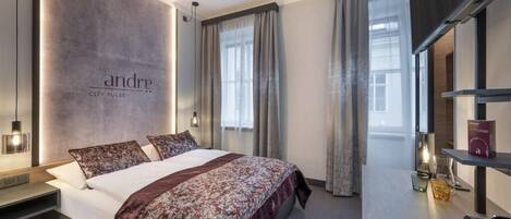 A modern hotel room with a large bed, a bedside table, a desk, and a view of the city.