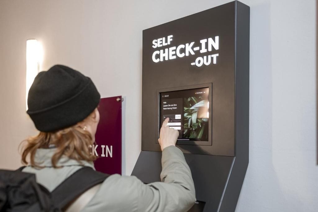 A person using a self-check-in kiosk with a screen displaying a menu.