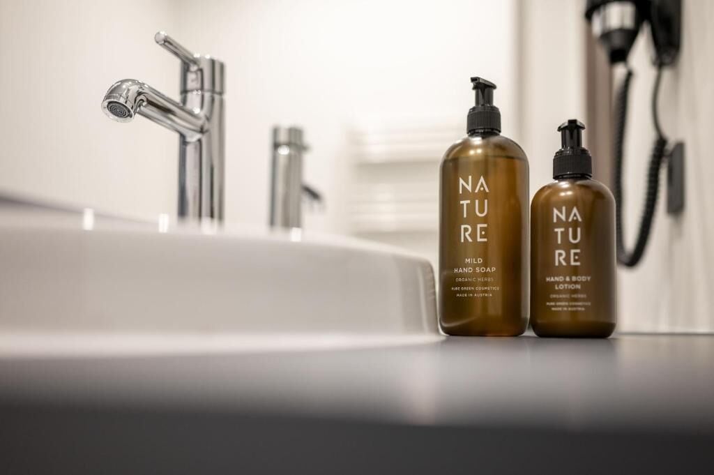 A bathroom sink with two Nature brand hand soap bottles.