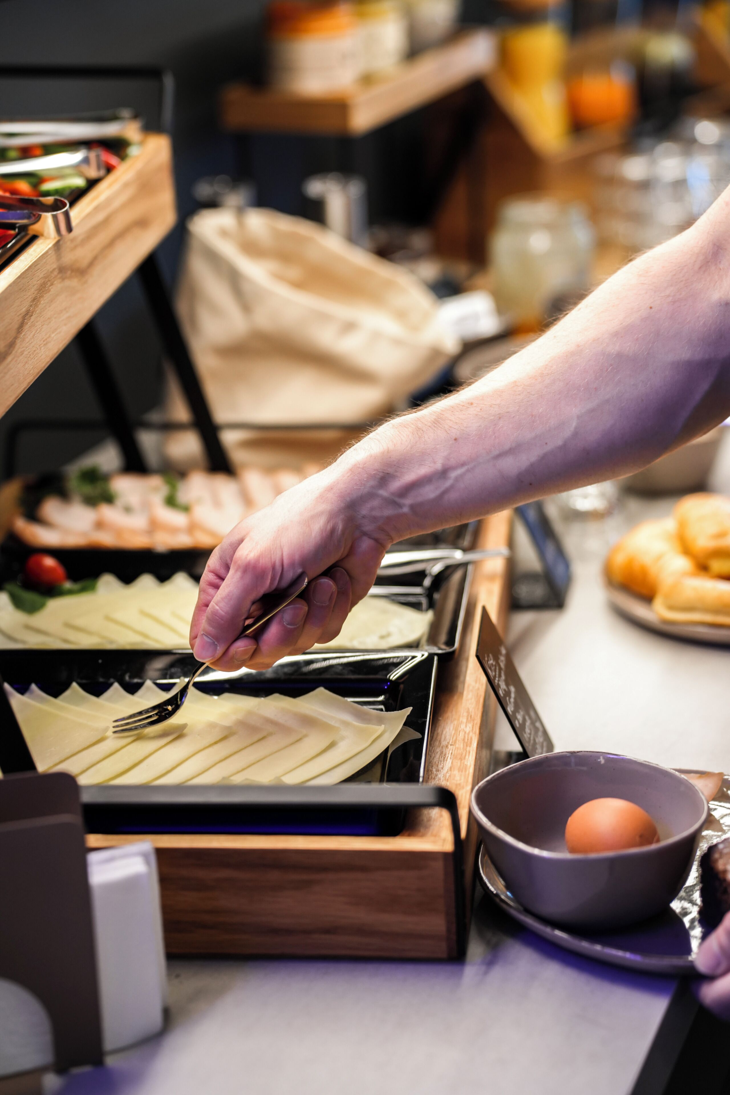 Una mesa de buffet con diferentes alimentos y una persona servándose.
