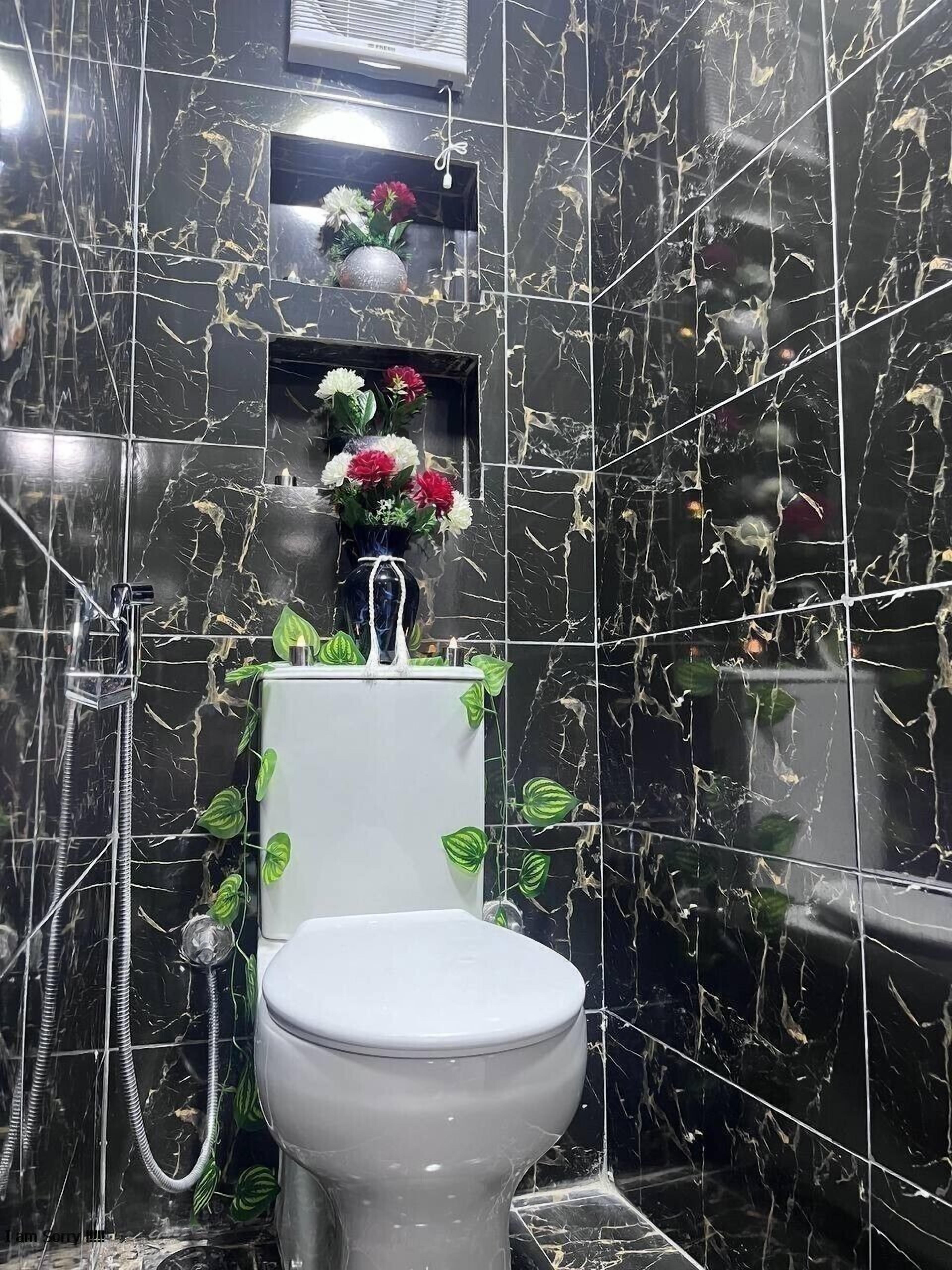 A bathroom with a white toilet, a shower, and a marble wall with a crackled pattern.