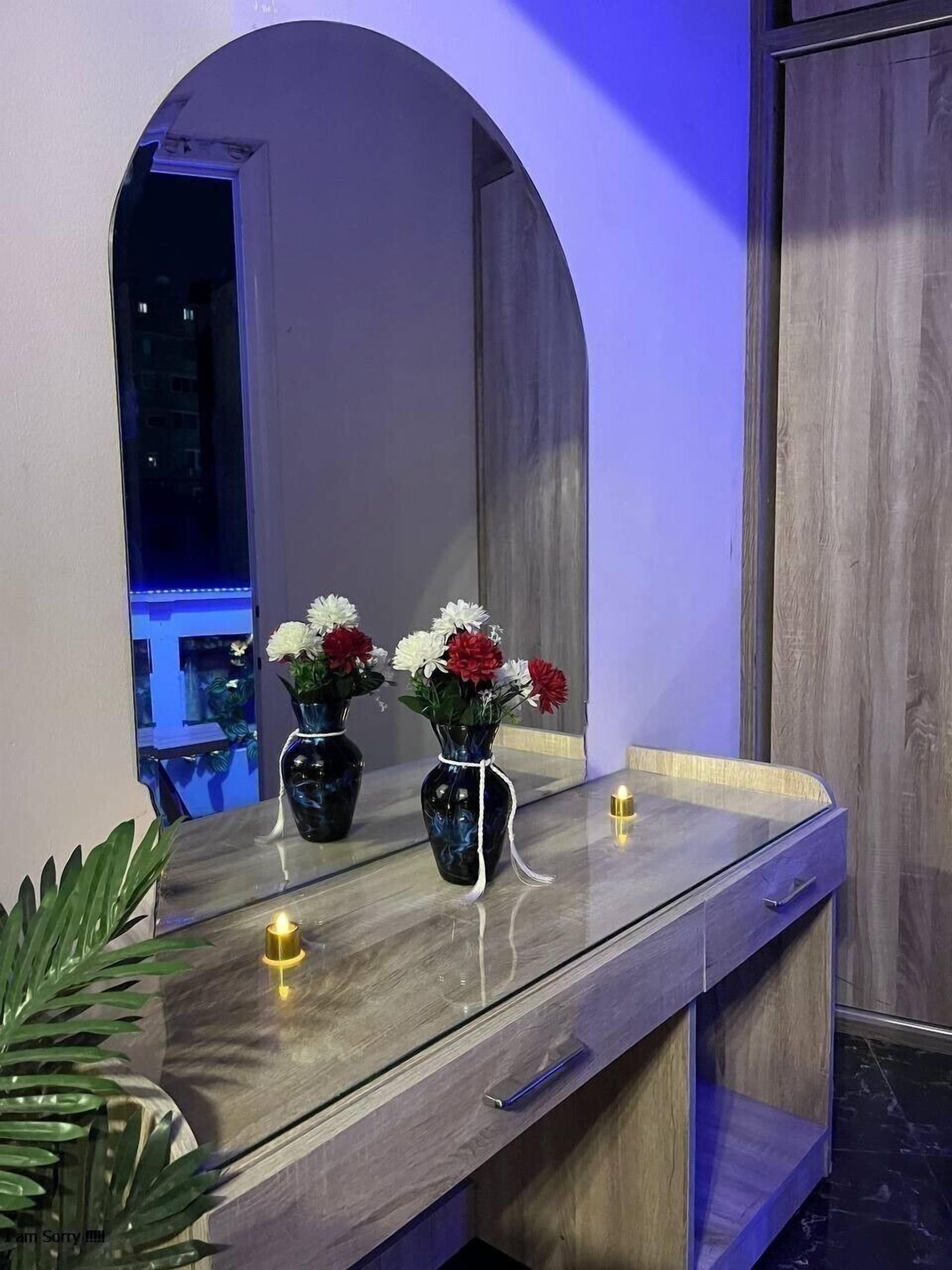 A modern bathroom with a vanity, two vases with flowers, a mirror, and a plant.