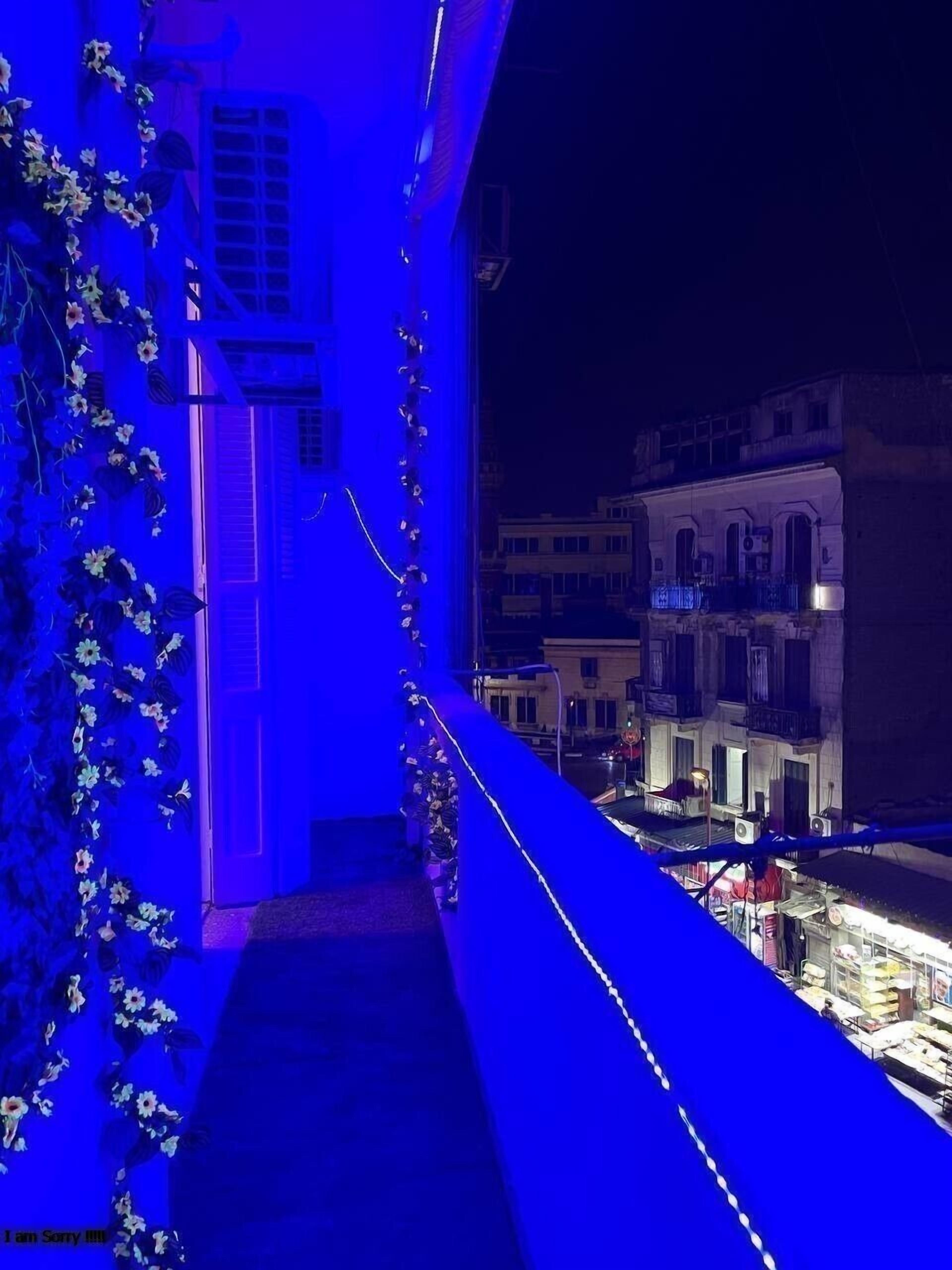 A night view of a building with a balcony, illuminated by blue lighting.