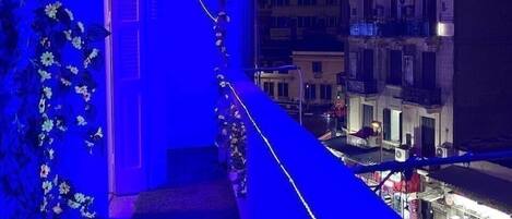 A night view of a building with a balcony, illuminated by blue lighting.