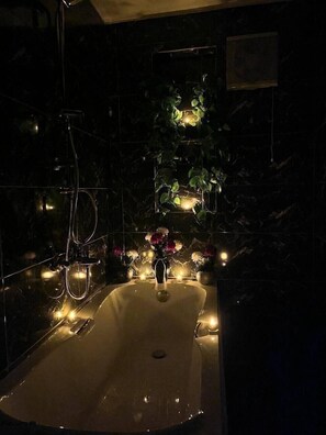 A dimly lit bathroom with a freestanding bathtub, a shower, and a wall-mounted sink. - Downtown view studios (Cairo)