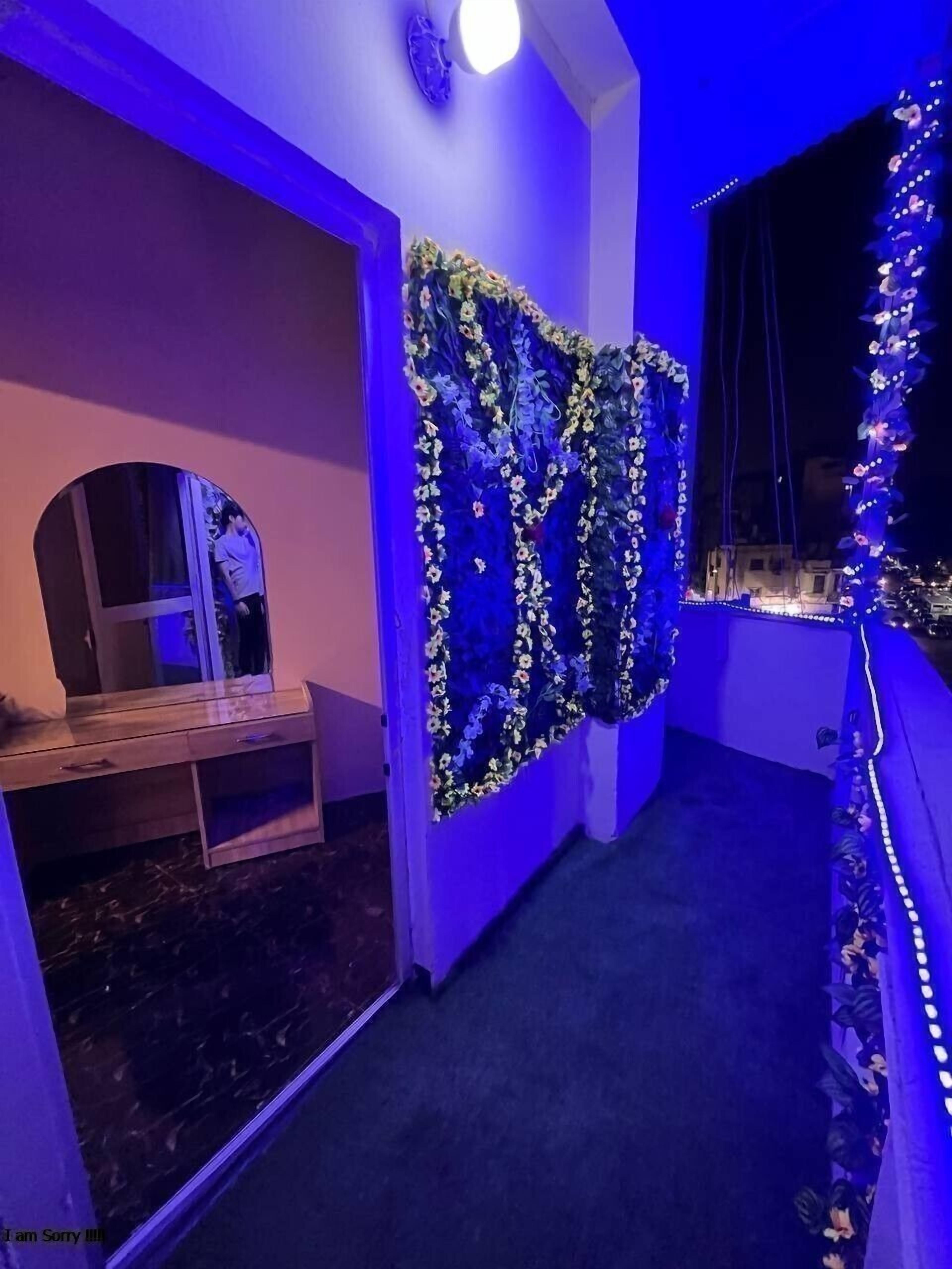 A room with a blue-lit wall, a wooden bench, and a window with a view of buildings.