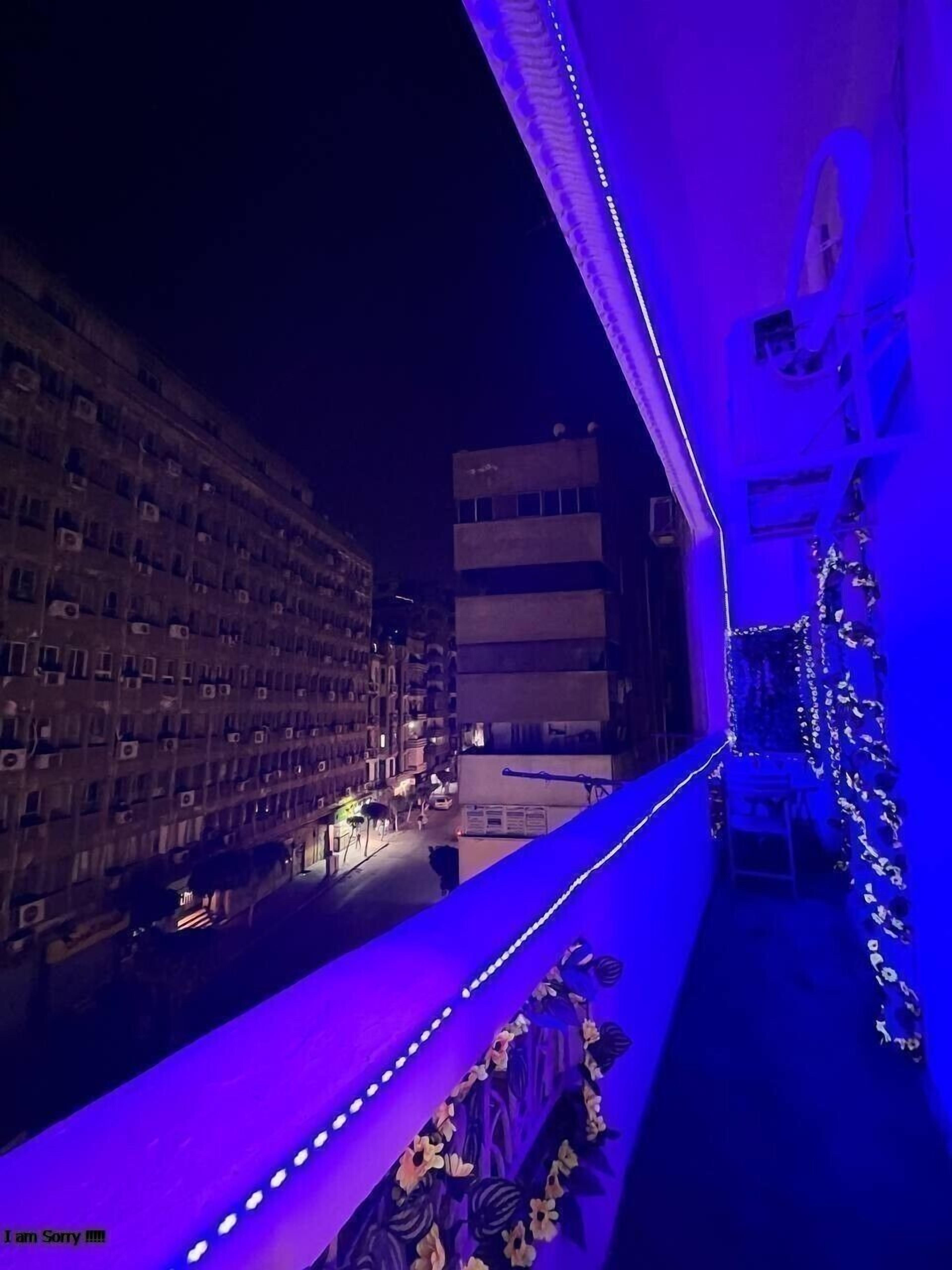A balcony with a view of a cityscape at night, illuminated by blue lights.