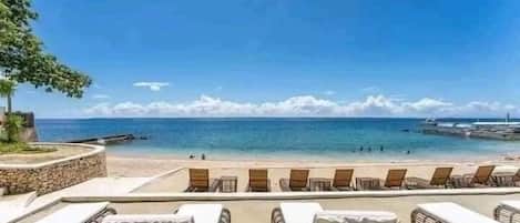 A beachside view with lounge chairs and a clear view of the ocean.