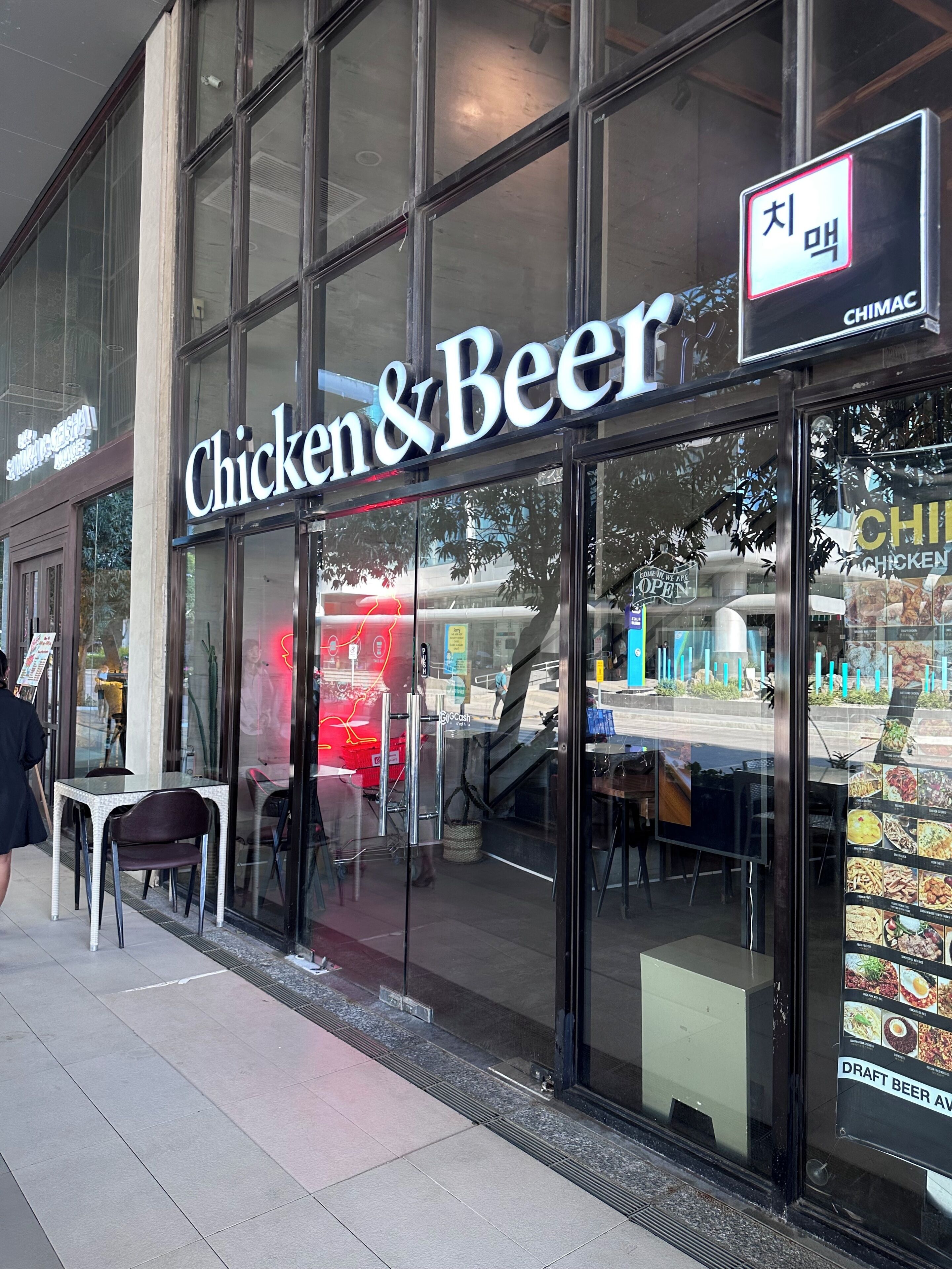 Une devanture de magasin avec une enseigne indiquant « Poulet et bière », dotée d’une entrée en verre et d’un panneau affichant le menu, visible à travers la vitrine.