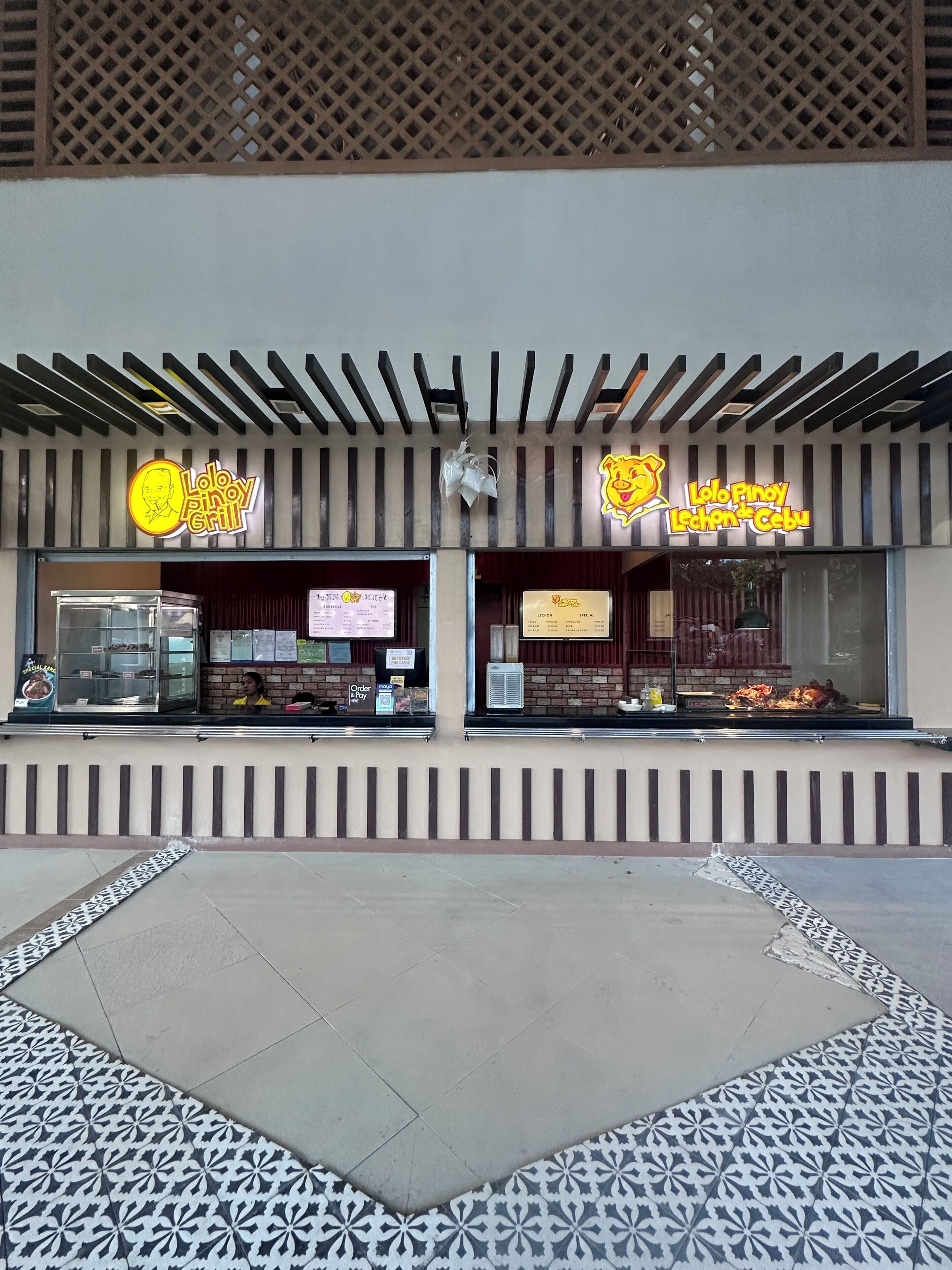 A restaurant with two signs, a glass display case, and a patterned floor.