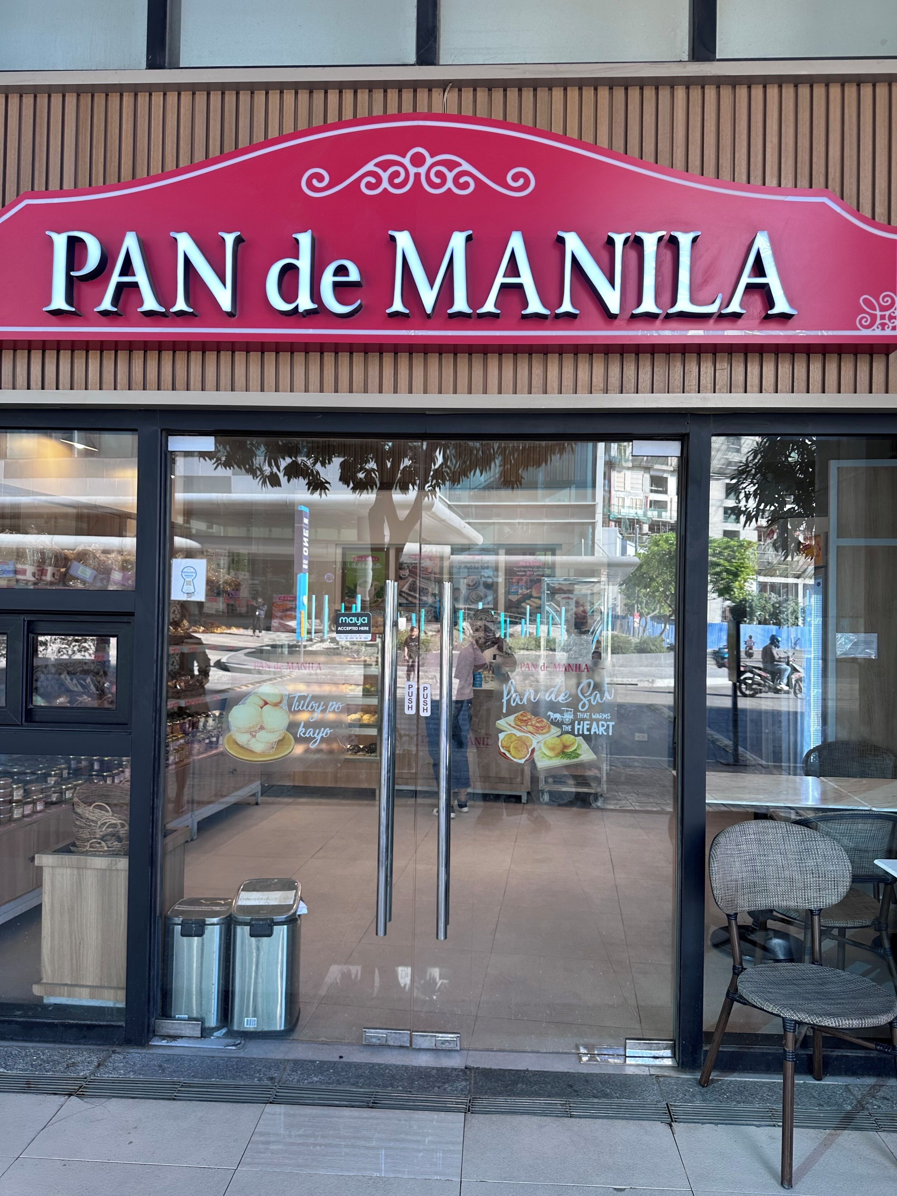En butik med ett skyltfönster där det står ”PAN DE MANILA” och där bakverk visas upp.