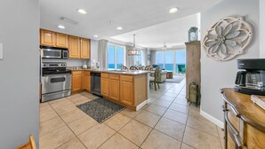A spacious kitchen with wooden cabinets, stainless steel appliances, and a large island. - Grandview East 1201 (Panama City Beach)