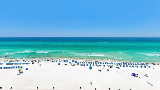 A beach with white sand, clear turquoise water, and a clear blue sky. - Grandview East 1201 (Panama City Beach)