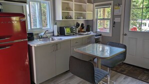 Eine kompakte Küche mit einem roten Kühlschrank, einem eingebauten Backofen und einer kleinen Essecke mit einem Tisch und zwei Stühlen.