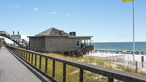 A boardwalk leading to a building labeled 'Whale's Tail Restaurant' with a beach and umbrellas in the background. - Augusta Village Sandestin by Gibson BR  (Miramar Beach)