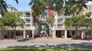 A multi-story hotel with balconies, a central archway, and a street view. - Augusta Village Sandestin by Gibson BR  (Miramar Beach)
