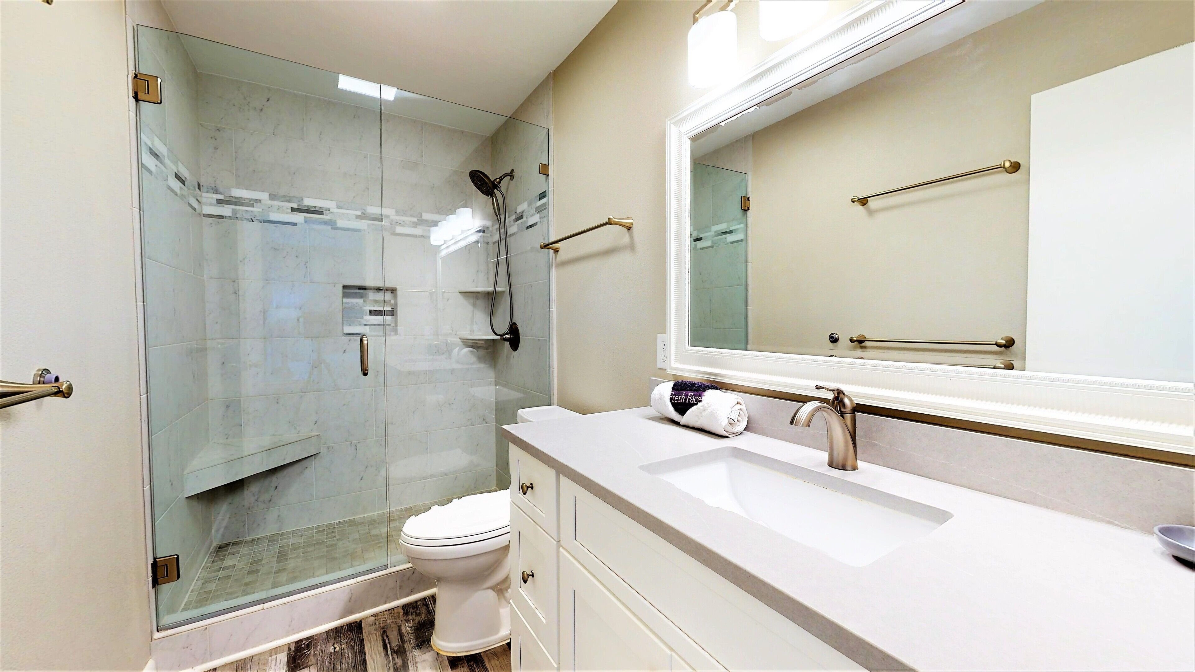 A modern bathroom with a glass-enclosed shower, a white sink, and a large mirror.